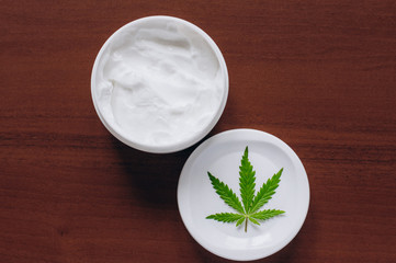 Moisturizing hemp hand cream in dose with green cannabis leaf. Cannabis cosmetics. Cream from biological and ecological plants of hemp vegetable pharmaceutical oil CBD