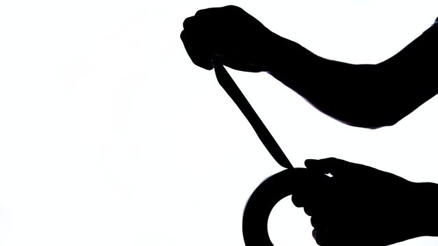 A close-up of Man's hand tearing off a piece of duct tape roll. Black and white shot, isolated