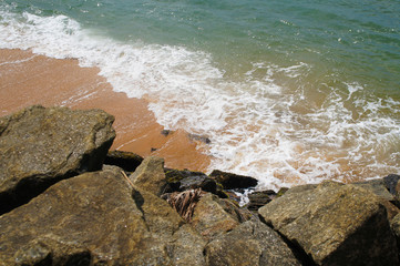 Southern tropical summer ocean coast with rocks and rocks. Lagoon with a yellow sandy beach and azure water.