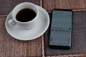 White coffee cup with mobile phone on table.Coffee time