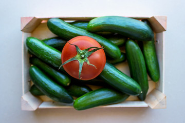 Tomatoes and cucumbers in a wooden crate. Concept- fresh organic vegetables, healthy food from garden. Selective focus.