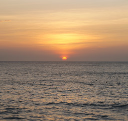 Southern tropical summer ocean coast at sunset. Lagoon with waves in which the sun is reflected.
