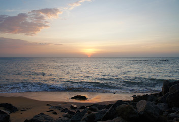 Fototapeta na wymiar Southern tropical summer ocean coast at sunset. Lagoon with waves in which the sun is reflected.