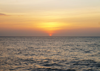 Southern tropical summer ocean coast at sunset. Lagoon with waves in which the sun is reflected.