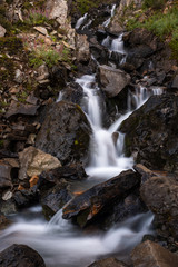 A close a small roadside waterfall as it tumbles on rocks on the dirt track road leading up to the Salmon Glacier, British Columbia, Canada, nobody in the image