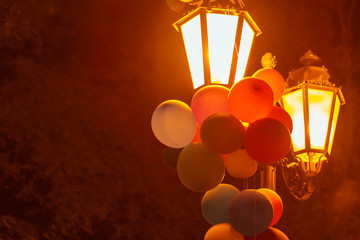 Multicolored balloons on a lantern in a night city park.