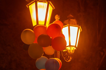 Multicolored balloons on a lantern in a night city park.