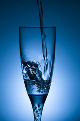 glass of water with splash on blue background