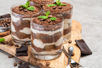 Classic tiramisu dessert in a glass on dark concrete background
