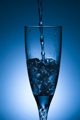 glass of water with splash on blue background