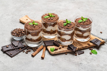 Classic tiramisu dessert in a glass on dark concrete background