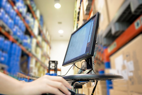 Focus on the computer in the warehouse Blurred background is a stock of many products.