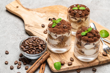Classic tiramisu dessert in a glass on dark concrete background