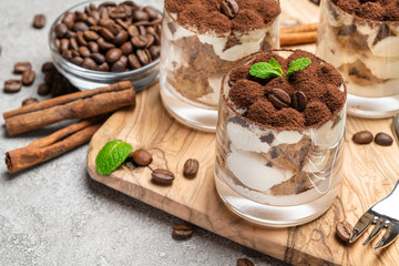 Classic tiramisu dessert in a glass on dark concrete background