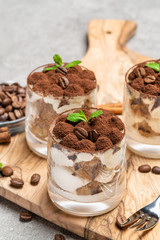 Classic tiramisu dessert in a glass on dark concrete background