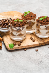Classic tiramisu dessert in a glass on dark concrete background