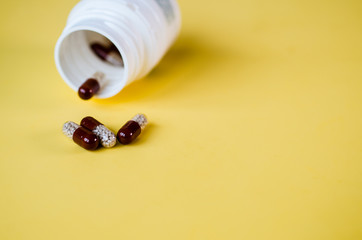 Capsules containing gastro-resistant granules spill out of a white container