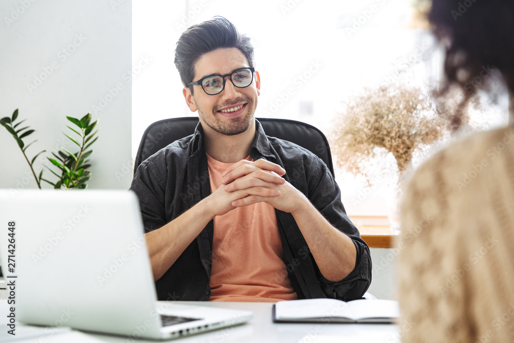 Wall mural Smiling man in eyeglasses sitting on meeting with his colleague