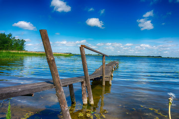 Old rickety wooden jetty leading into a lake