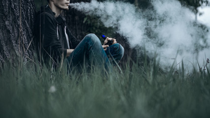 A man smokes an electronic cigarette outdoors