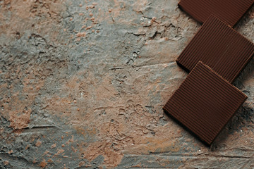 Slices of bitter chocolate on a concrete brown background with copy space