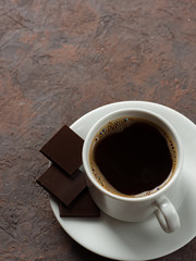 White Cup of coffee and bitter chocolate on concrete background