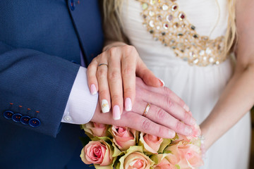 Hands of the groom and bride with rings and bridal bouquet