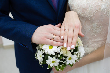 Hands of the groom and bride with rings and bridal bouquet