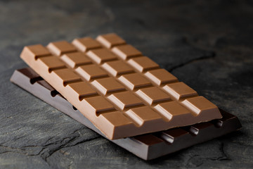 A slab of milk chocolate on top of a slab of dark chocolate isolated on black slate. Space for...