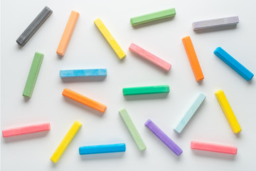 flat lay of multicolor chalks like background on white, concept of education or business