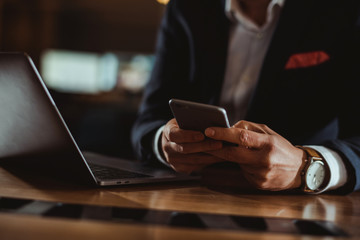 Close-up of hands using phone and laptop