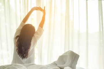 Fotobehang Asian women waking up stretching in bed at home, morning and sunny day.  Lifestyle Concept © freebird7977