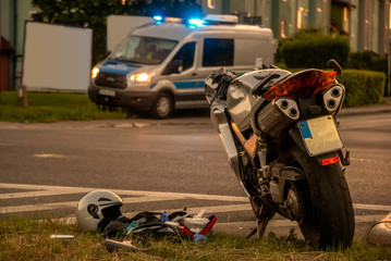 Motorcycle destroyed due to collision with the car at the crossroads.In the background there is a visible police car with lights signals turned on