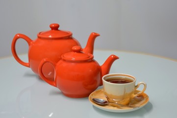 Two teapots and cup of tea on white background