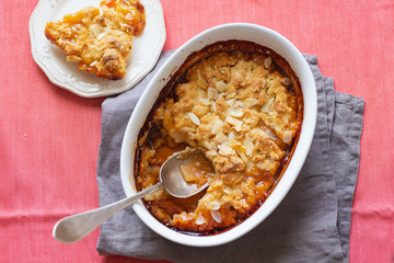 Overhead image of plum cobbler with almond flakes and cream