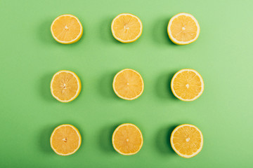 Top view of fresh and yellow cut lemons on colorful green background