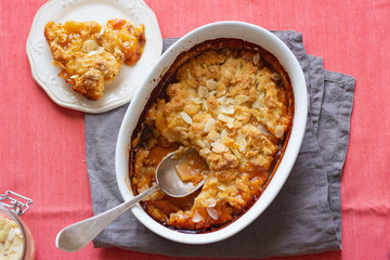 Overhead image of plum cobbler with almond flakes and cream