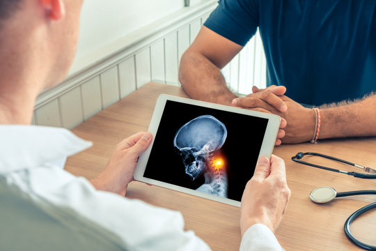 Doctor holding a digital tablet with x-ray of skull head of the patient. Pain in the neck. Migraine headache and back pain concept