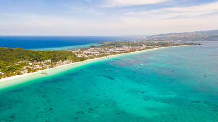 Fototapeta premium The coast of the island of Boracay. White beach and clear sea. Seascape with a beautiful coast in sunny weather. Residential neighborhoods and hotels on the island of Boracay, Philippines, view from