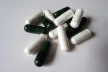 Handful of white capsules of magnesium citrate and green capsules of multivatamins