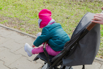 Little girl sitting in a baby carriage on the street