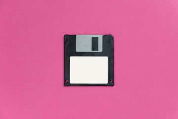 black floppy disk on pink background. retro magnetic storage