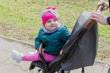 Little girl sitting in a baby carriage on the street