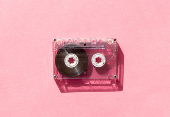 retro transparent audio cassette tape on pink background. vintage music technology