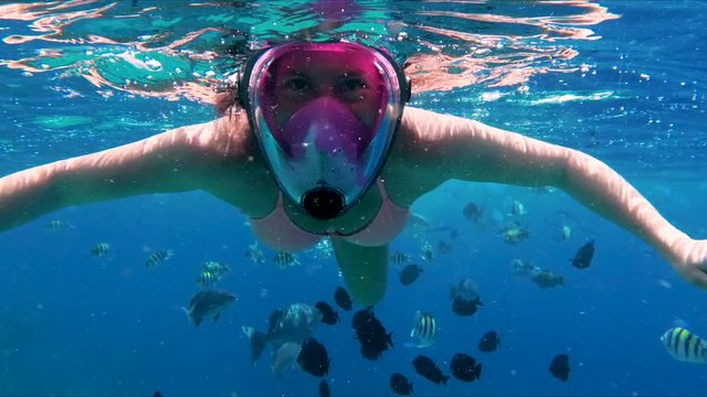 Underwater swimming with tropical fish in Red Sea. Snorkeling girl waving hands to the camera close up