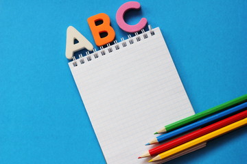 ABC-the first letters of the English alphabet on a blue background. Notebook and pencils of...