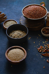 Various types of rice and grains with spices on blue background. Brown rice and mixed wild rice.