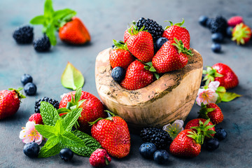 Großaufnahme von frischen Brombeeren, von Blaubeeren, von Erdbeeren und von grünen Minze  Blättern