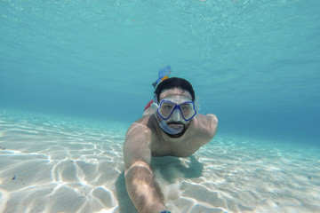 Young man swims in the sea - Millennial does snorkeling in the ocean in the summer