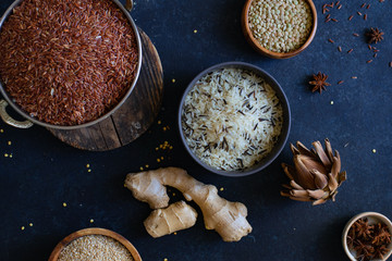 Various types of rice and grains with spices on blue background. Brown rice and mixed wild rice.